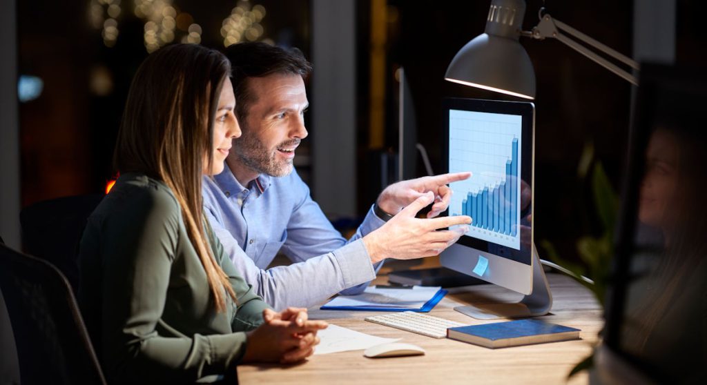 Imagem mostra contadora e empresário analisando um dashboard no computador para simular como começar a fazer BPO Financeiro