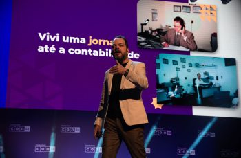 Imagem mostra Anderson Hernandes palestrando no palco, com sua história de vida na Contabilidade no slide de fundo, para mostrar que Contabilidade dá dinheiro