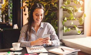 Empresária sorrindo mexendo no celular, para ilustrar como criar uma bio para Instagram de Contabilidade