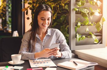 Empresária sorrindo mexendo no celular, para ilustrar como criar uma bio para Instagram de Contabilidade