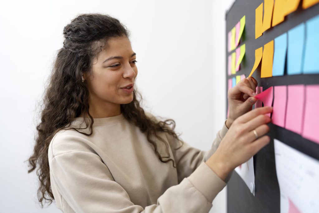 Imagem mostra jovem colando post its na parede para simbolizar um brainstorm de como escolher um nome para escritório de contabilidade