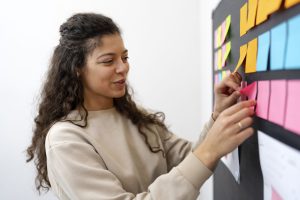 Imagem mostra jovem colando post its na parede para simbolizar um brainstorm de como escolher um nome para escritório de contabilidade