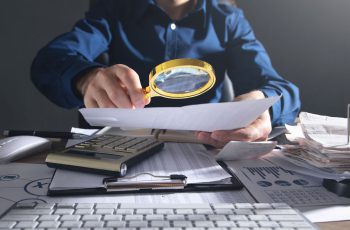 Empresário com lupa, para ilustrar a reforma tributária para contadores