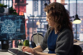 Mulher trabalhando com computador à frente remetendo à IA, para ilustrar ferramentas de IA para contadores