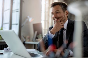 Imagem mostra jovem empresário sorrindo à frente do computador, para simbolizar as oportunidades tributárias para contadores